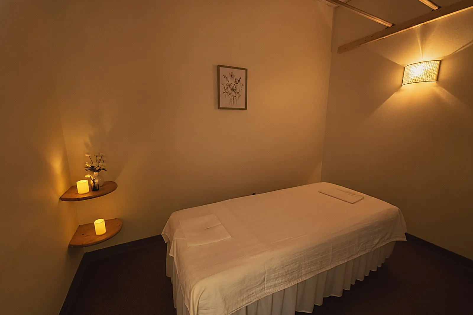 A candlelit treatment room at Day Massage in Chaska with a sheet-draped massage table